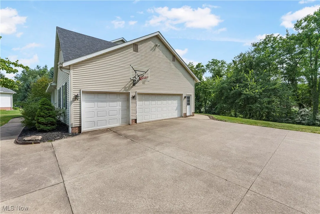 View of side of property with driveway and a shingled roof