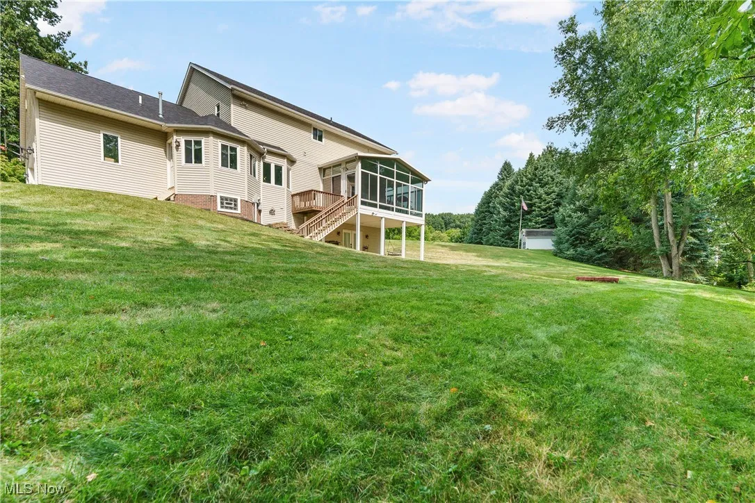 Rear view of house featuring a sunroom, stairway, a yard, and a wooden deck