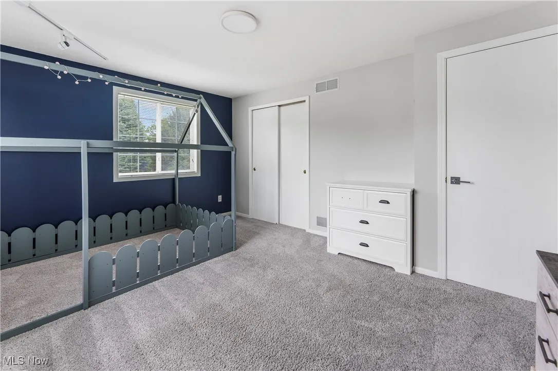 Unfurnished bedroom with carpet flooring, a closet, and track lighting