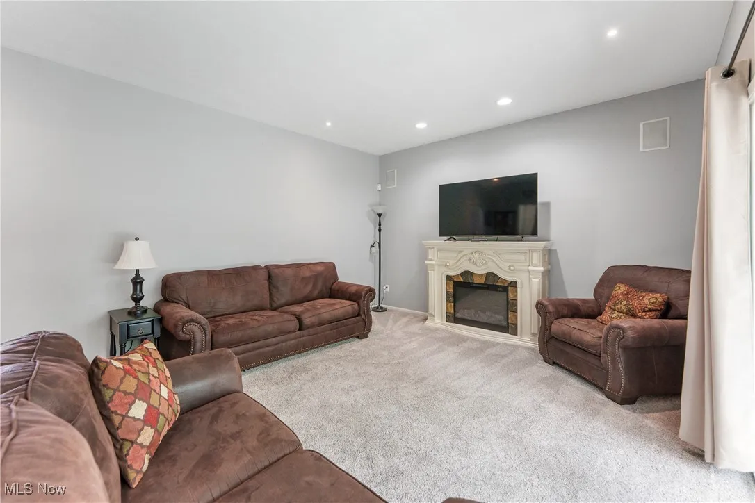 Living area featuring a fireplace, light colored carpet, and recessed lighting