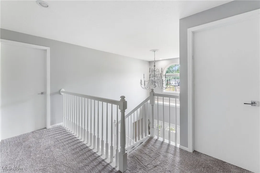 Stairs featuring carpet floors and a chandelier