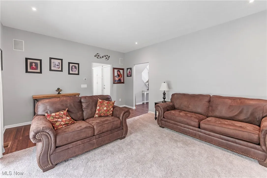 Carpeted living area with recessed lighting and wood finished floors