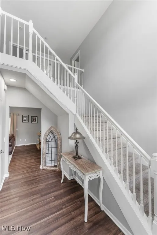 Stairway with a towering ceiling and wood finished floors
