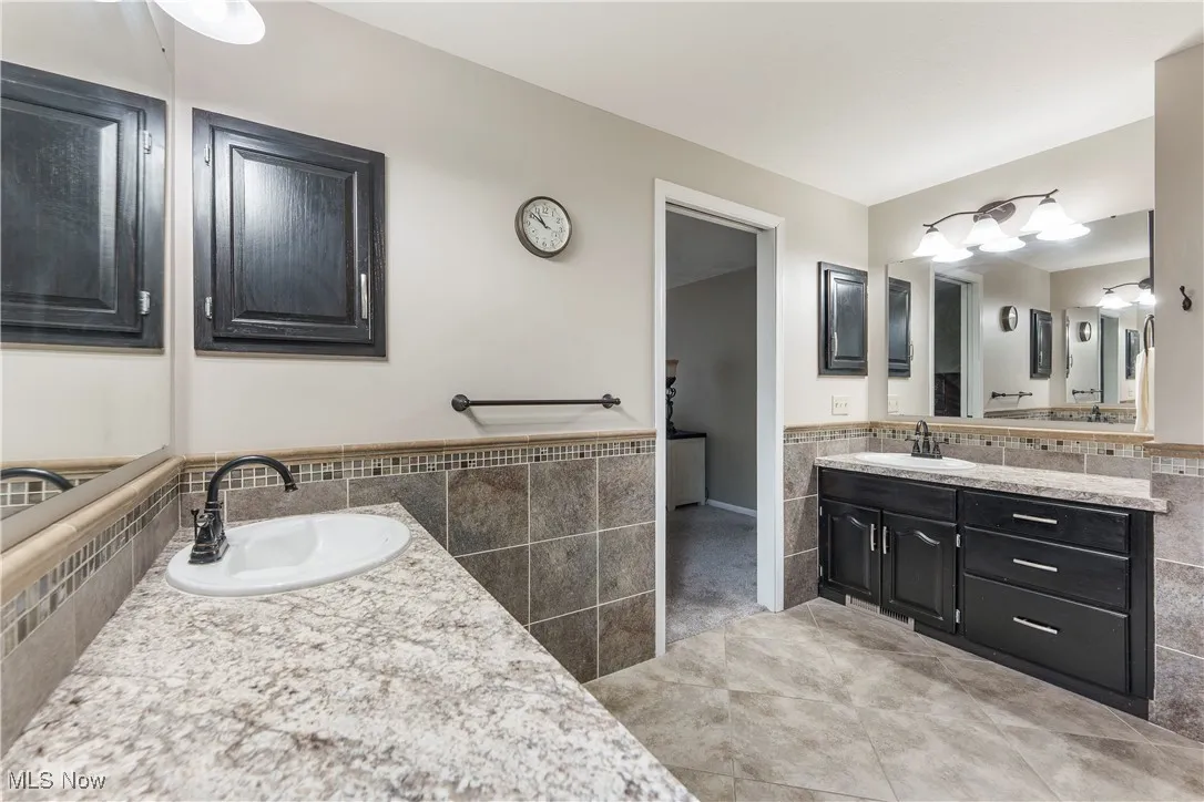 Bathroom featuring vanity, wainscoting, tile patterned flooring, and tile walls