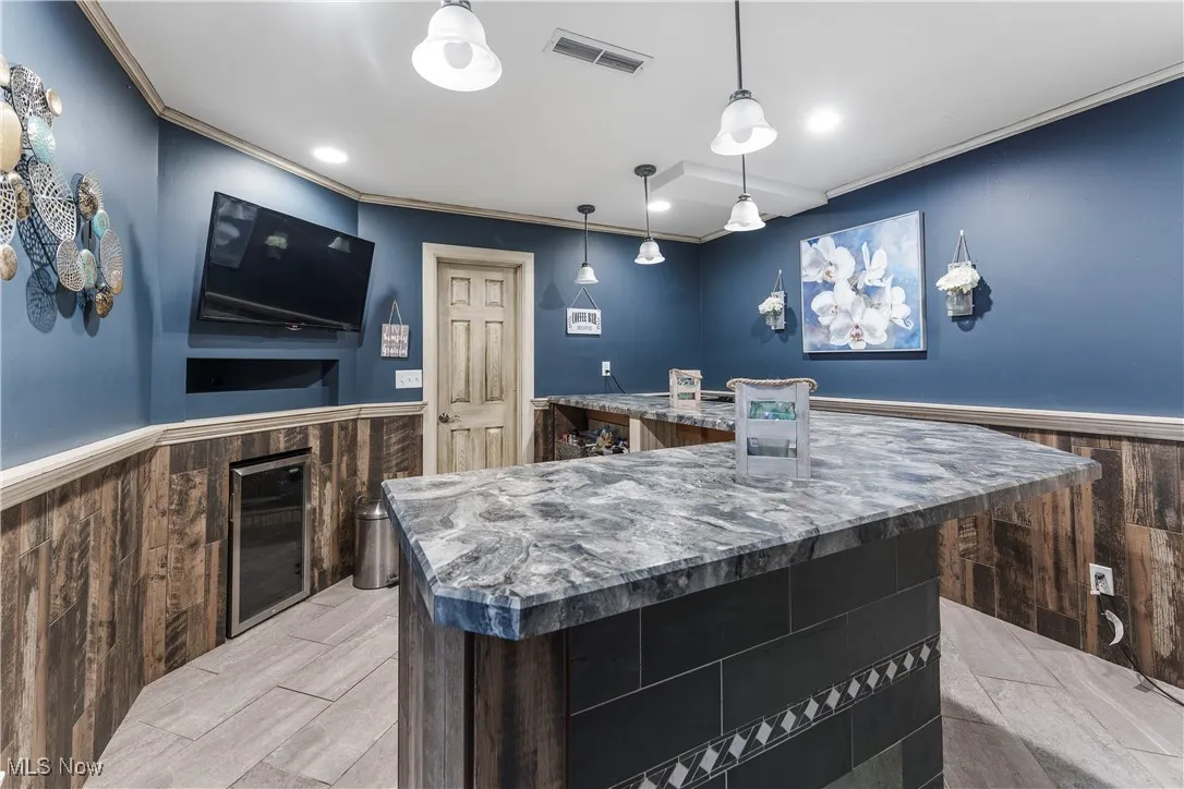 Kitchen featuring wainscoting, wooden walls, a spacious island, crown molding, and recessed lighting