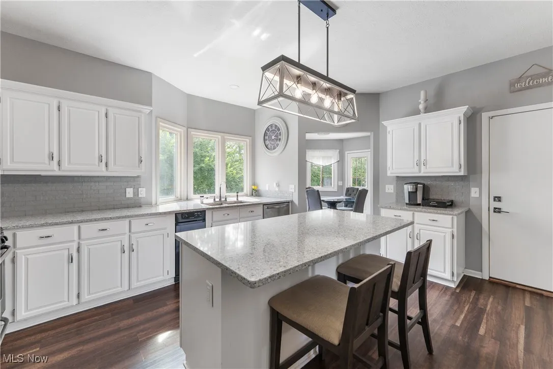 Kitchen featuring decorative backsplash, dark wood-style floors, white cabinets, and a kitchen island