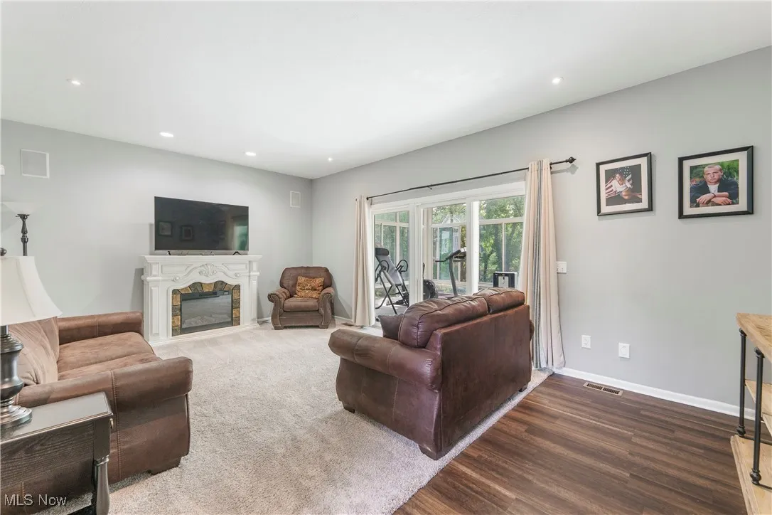 Living area featuring a glass covered fireplace, recessed lighting, and dark wood finished floors