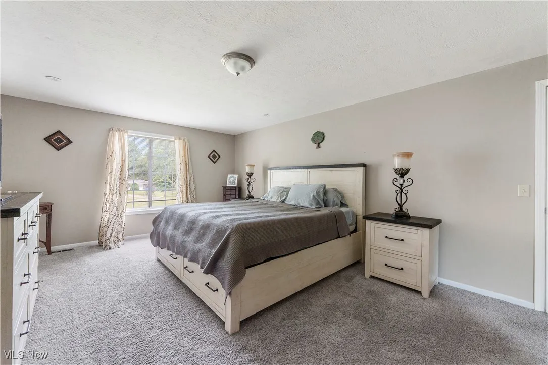 Bedroom with light colored carpet and a textured ceiling