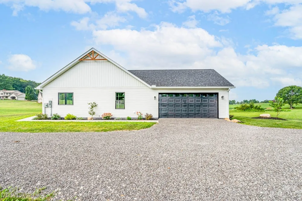 View of front facade with a front yard, driveway, roof with shingles, and a garage