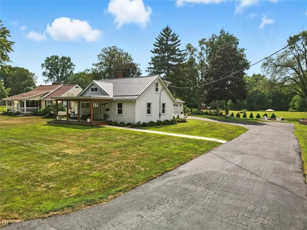 View of front of property with a metal roof, a standing seam roof, a porch, driveway, and a front yard