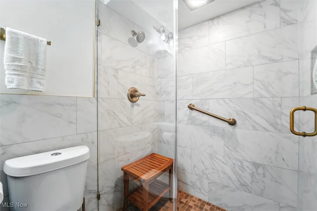 Bathroom featuring a tile shower and tile walls