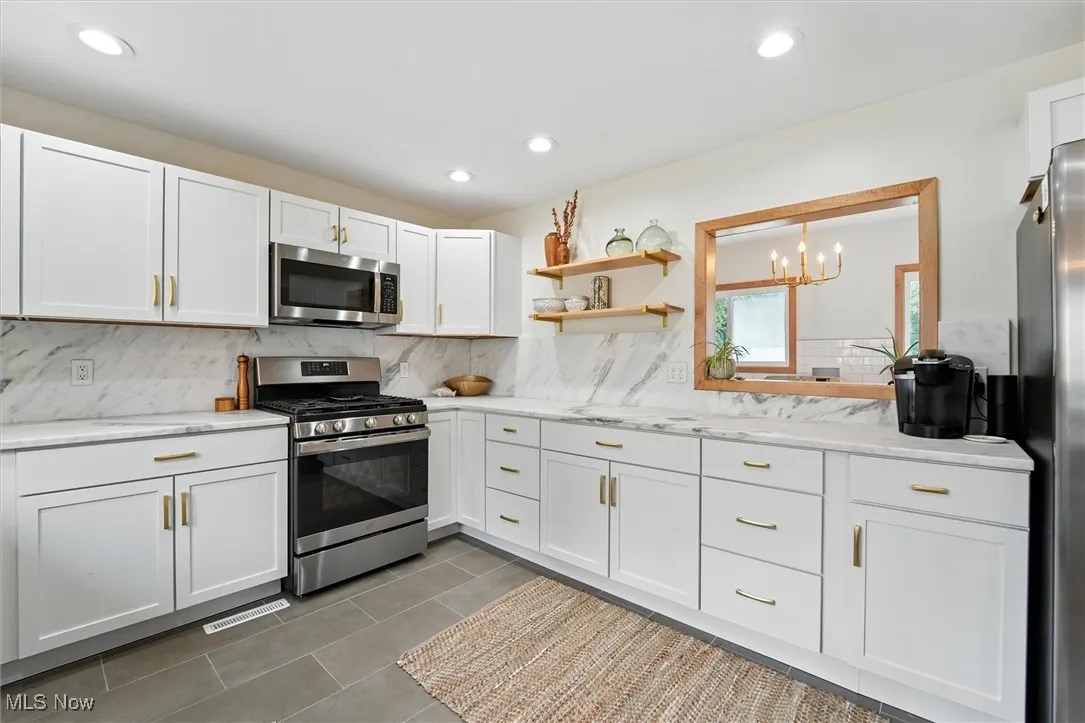 Kitchen with appliances with stainless steel finishes, backsplash, white cabinets, recessed lighting, and tile patterned flooring