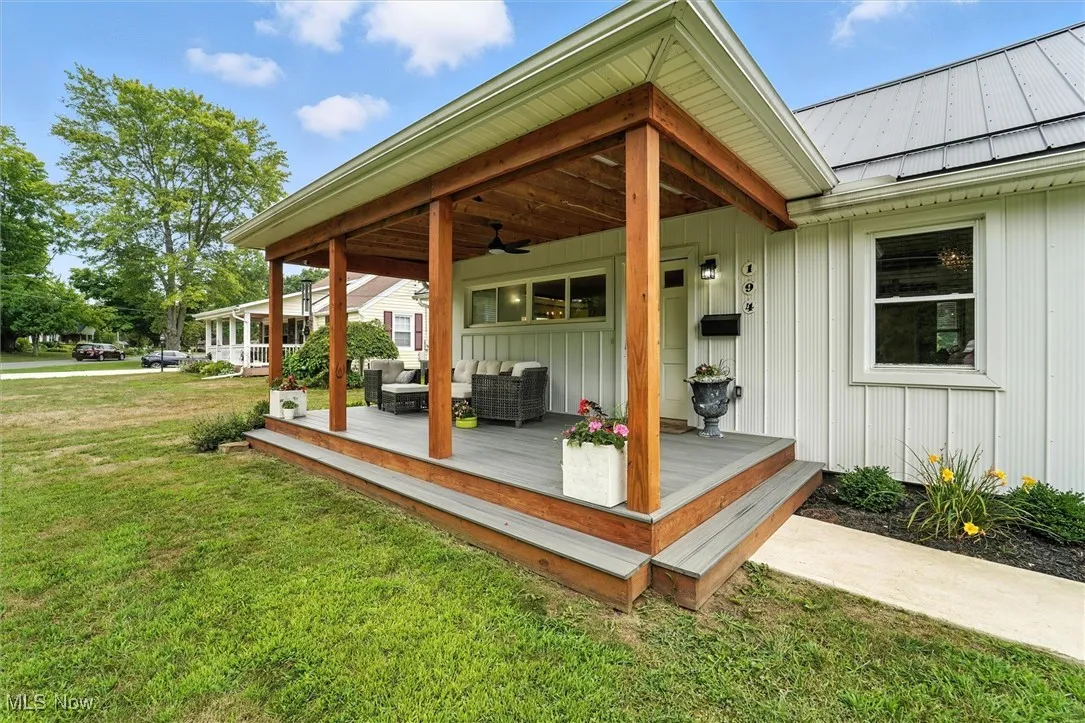 Wooden terrace with an outdoor living space, ceiling fan, and a lawn