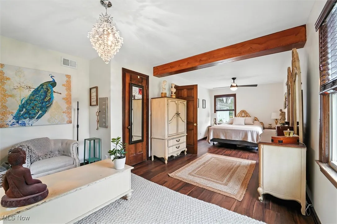 Bedroom featuring beam ceiling, dark wood-type flooring, a chandelier, and ceiling fan