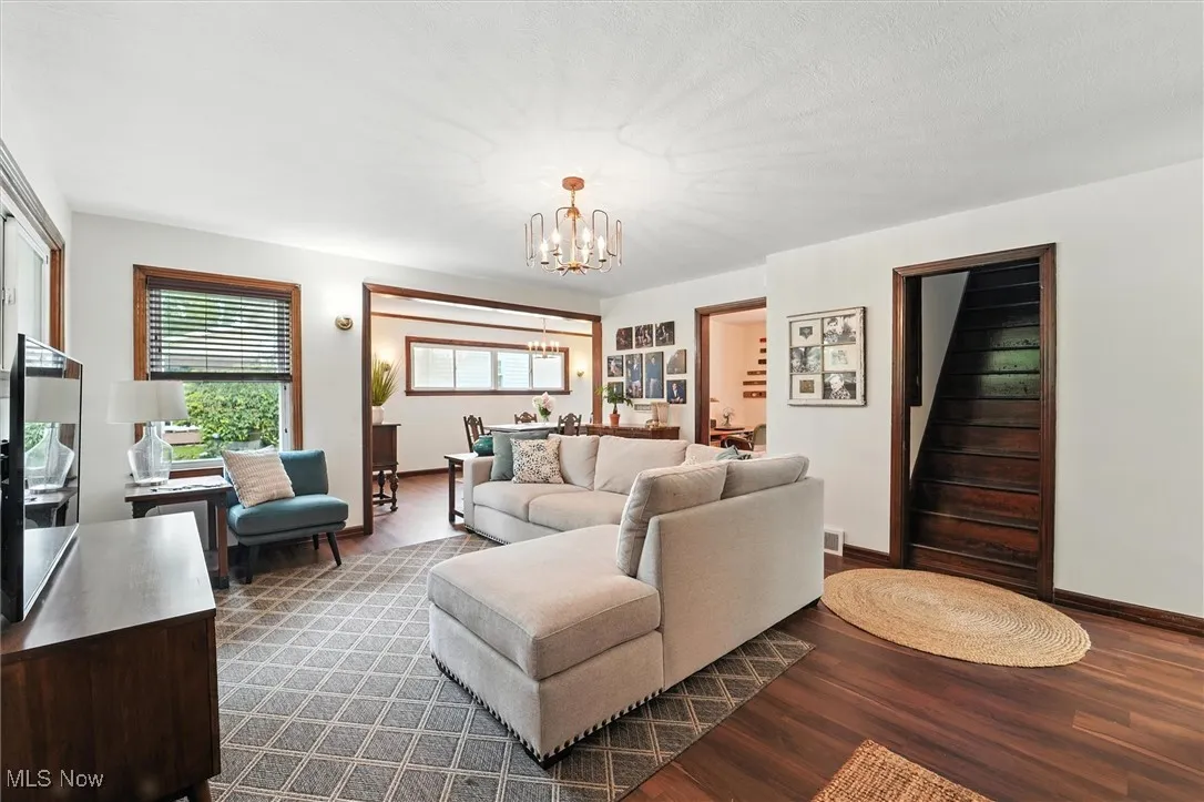 Living room with a chandelier, dark wood-style floors, and stairway