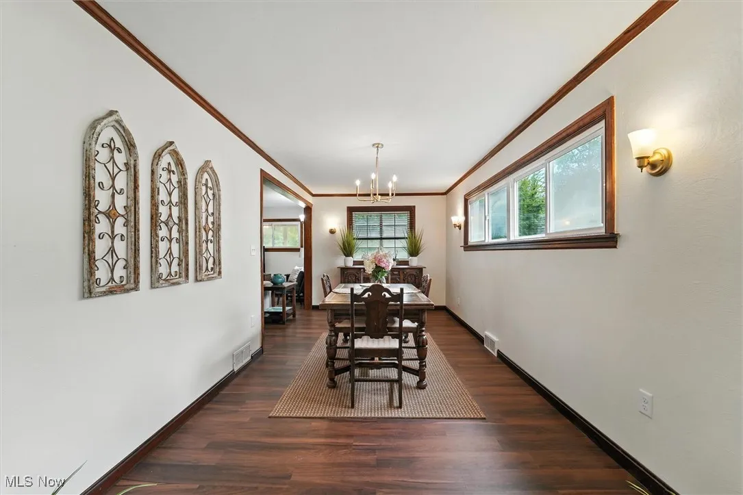 Dining space featuring ornamental molding, wood finished floors, and a chandelier