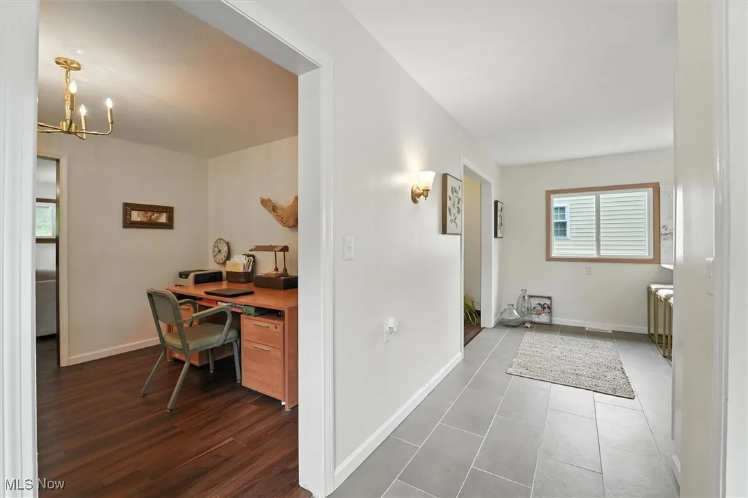 Hall featuring a chandelier, a desk, and tile patterned floors