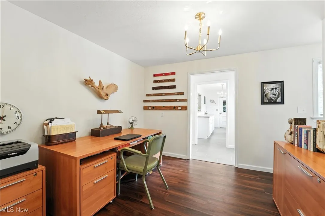 Office space with dark wood-type flooring and a chandelier