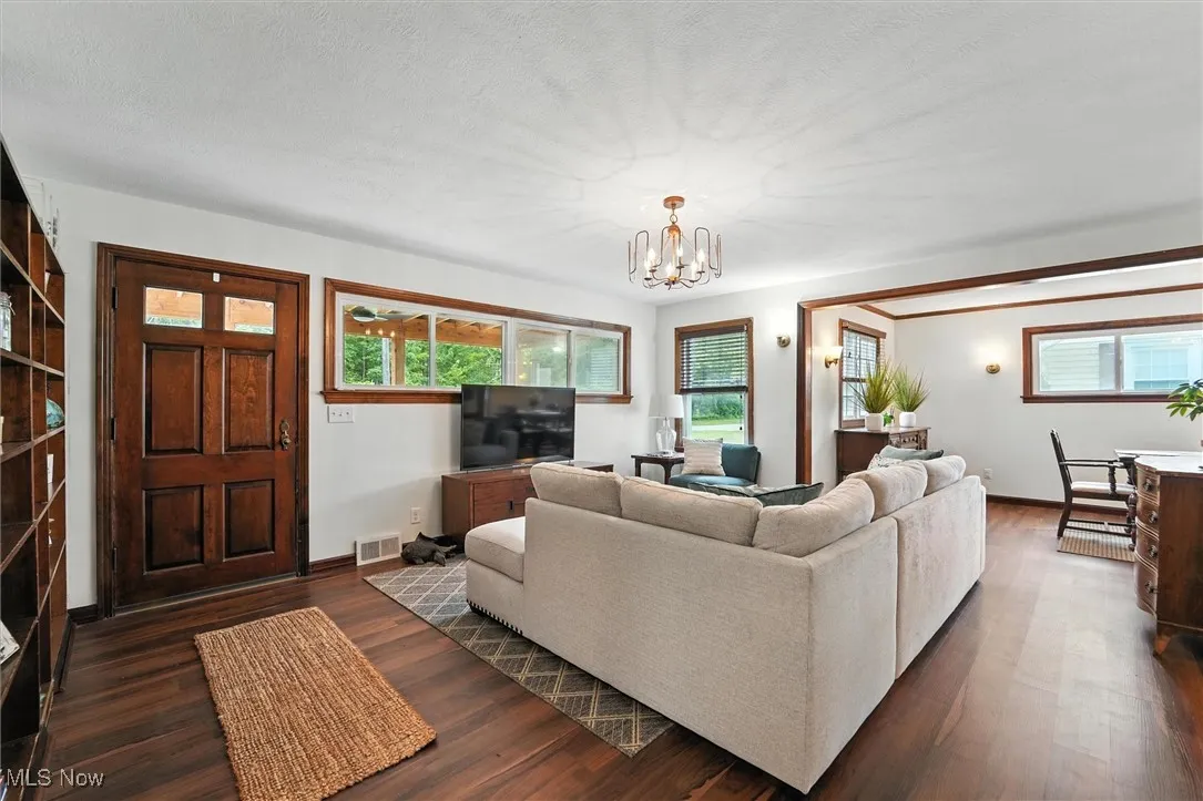 Living area featuring dark wood-style floors, a chandelier, and a textured ceiling