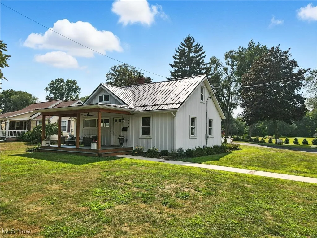 Modern farmhouse style home with a standing seam roof, a metal roof, a front lawn, board and batten siding, and covered porch