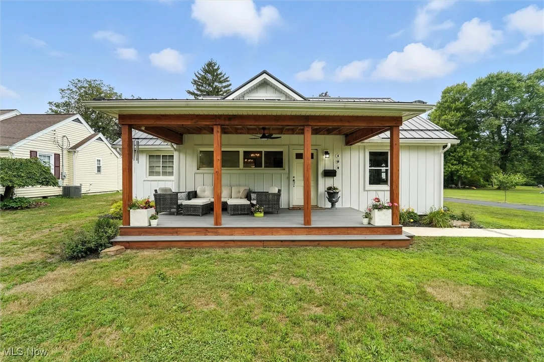 Rear view of house with an outdoor living space, board and batten siding, ceiling fan, and a lawn