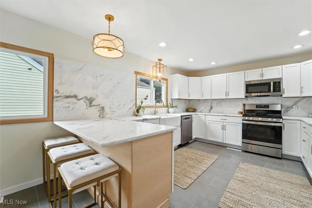 Kitchen featuring stainless steel appliances, a peninsula, tasteful backsplash, white cabinets, and recessed lighting