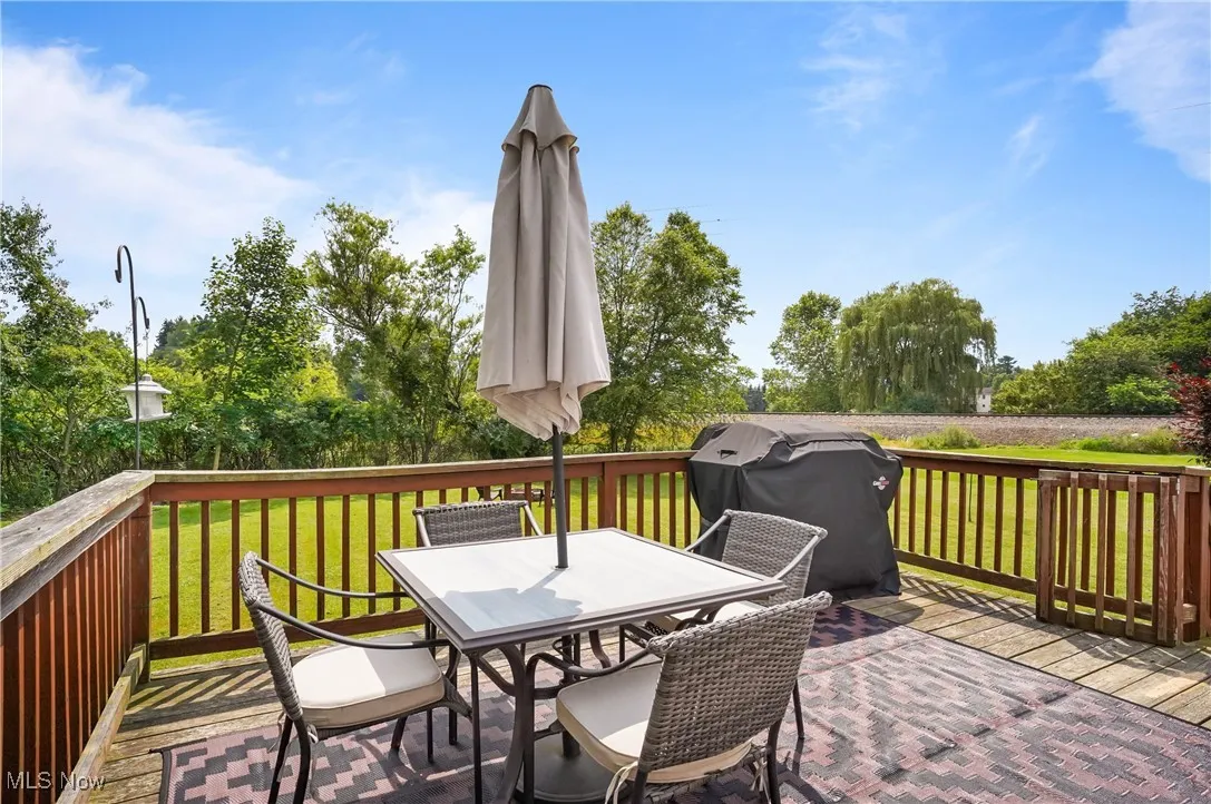 Deck with area for grilling, outdoor dining space, and a yard