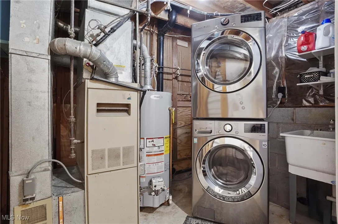 Laundry area with estacked washer and dryer, gas water heater, and heating unit