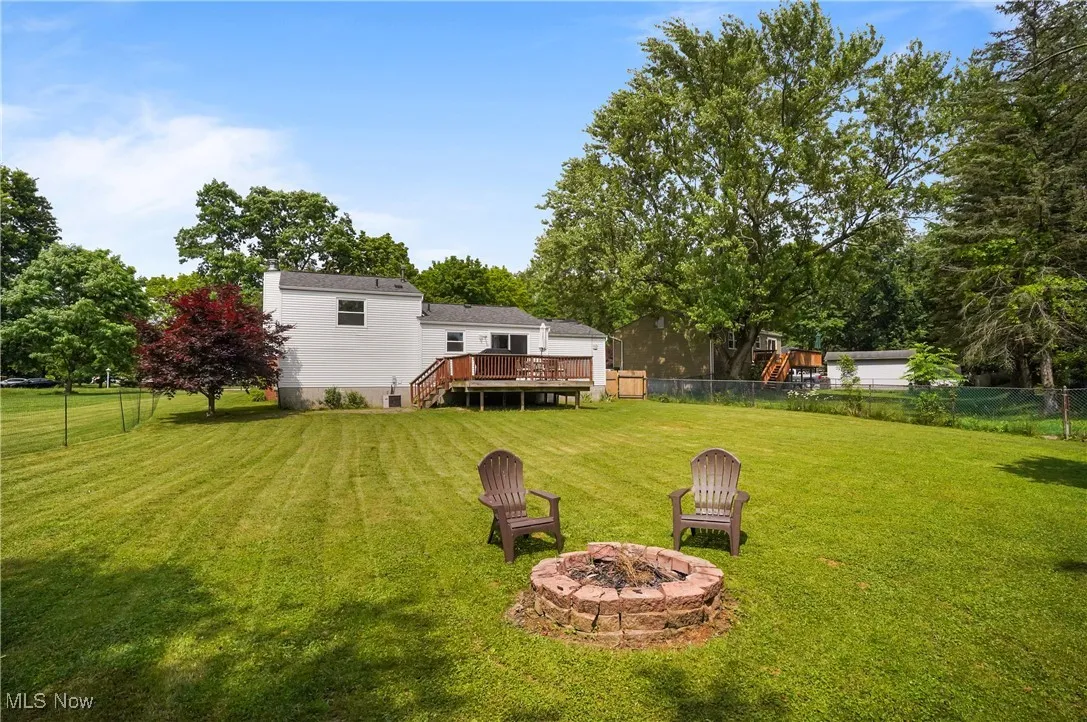 Fenced backyard featuring an outdoor fire pit, a wooden deck, and stairs