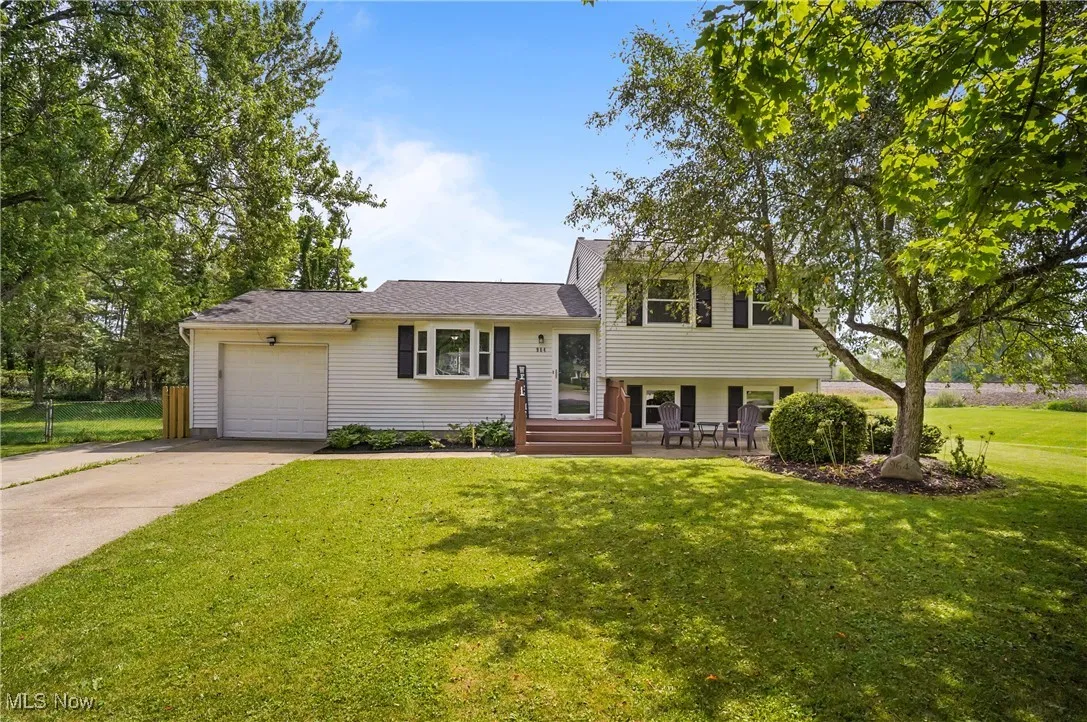Tri-level home with a garage, concrete driveway, and a front lawn