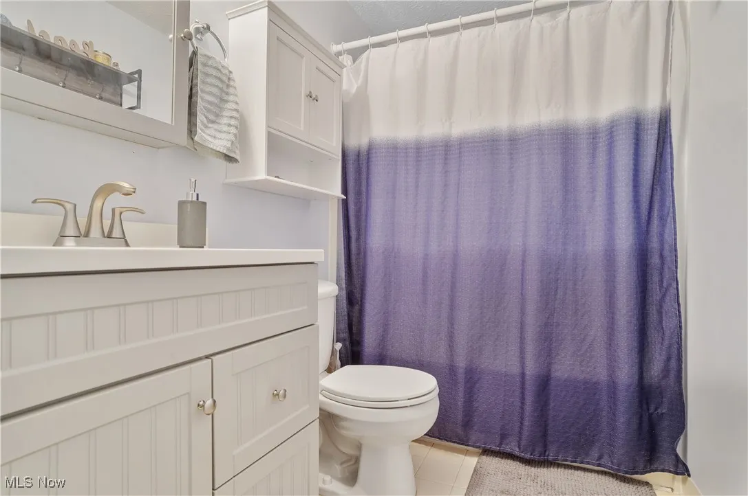 Full bathroom with vanity, tile patterned flooring, and curtained shower