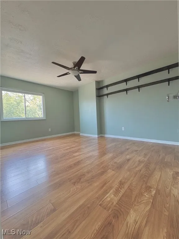 Unfurnished bedroom with a textured ceiling, light wood-style flooring, and ceiling fan