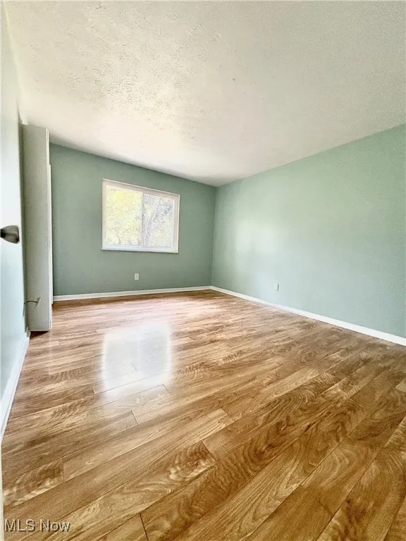 Unfurnished room featuring wood finished floors and a textured ceiling