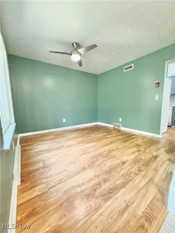 Spare room with light wood-style flooring, a textured ceiling, and a ceiling fan