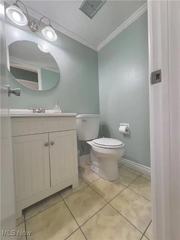 Bathroom with ornamental molding, vanity, a textured ceiling, and tile patterned flooring