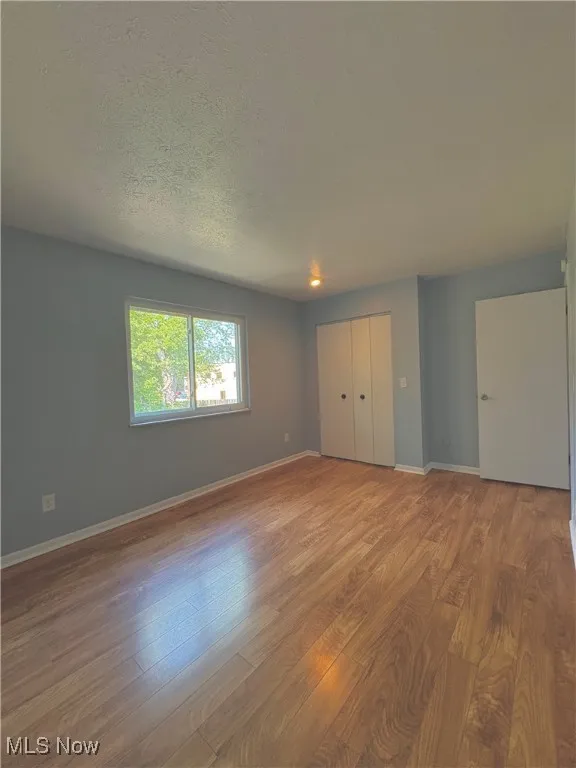 Unfurnished bedroom featuring wood finished floors, a textured ceiling, and a closet
