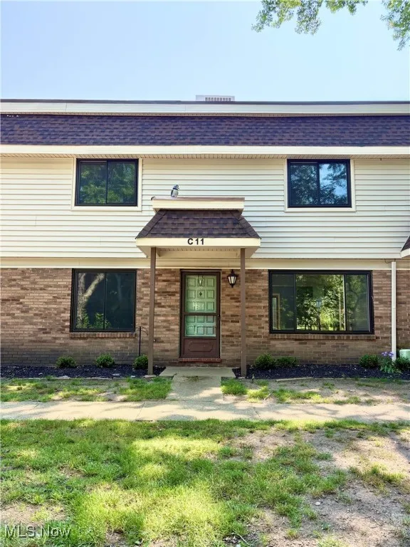 View of front of home with a shingled roof and brick siding