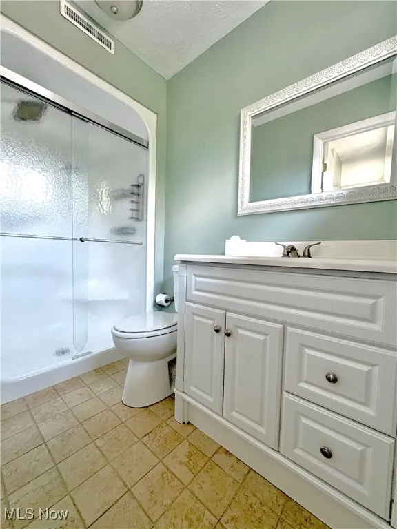 Bathroom with vanity, a textured ceiling, and a stall shower