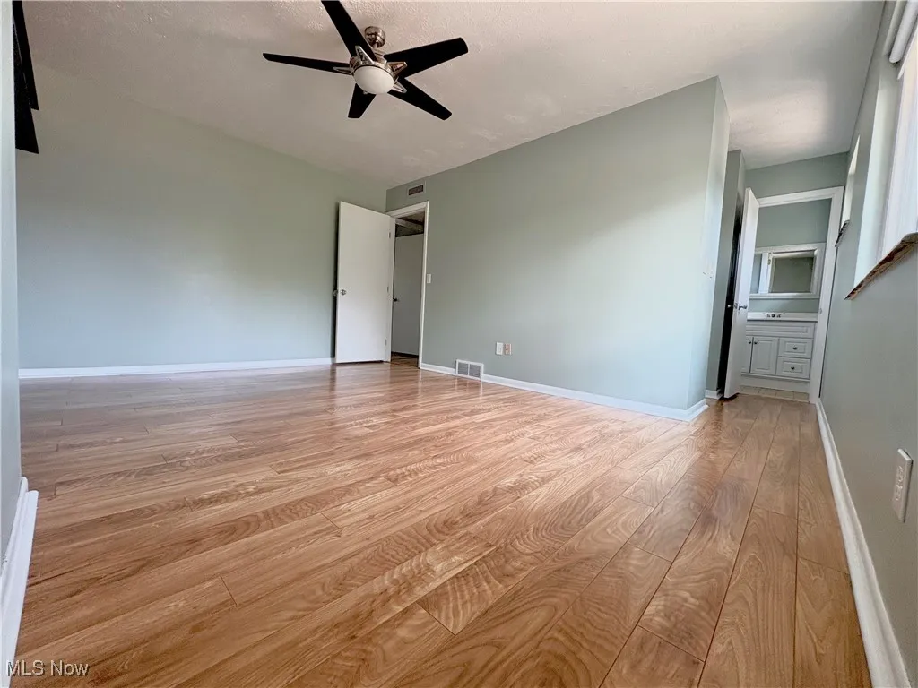 Empty room with light wood-style floors and a ceiling fan