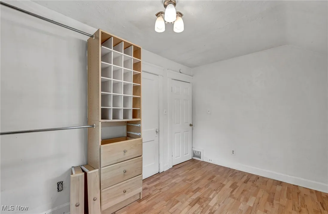 Unfurnished bedroom featuring light wood-style floors and vaulted ceiling