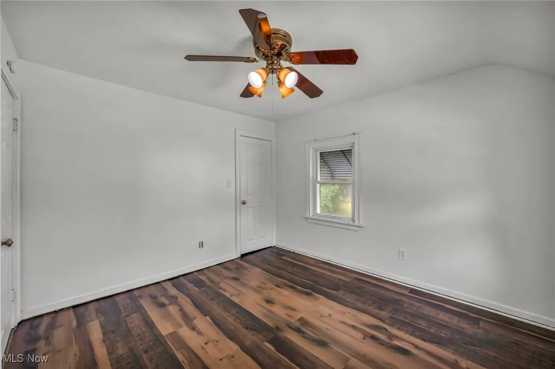 Empty room featuring dark wood-style flooring and ceiling fan