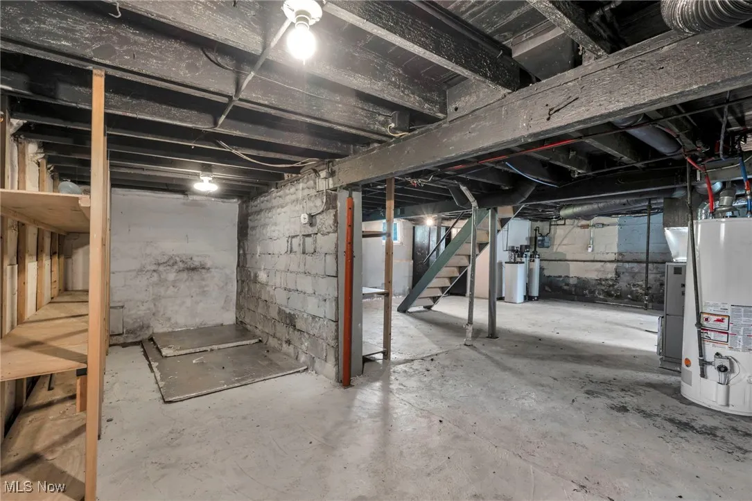 Unfinished basement with stairway, water heater, and a water softener system