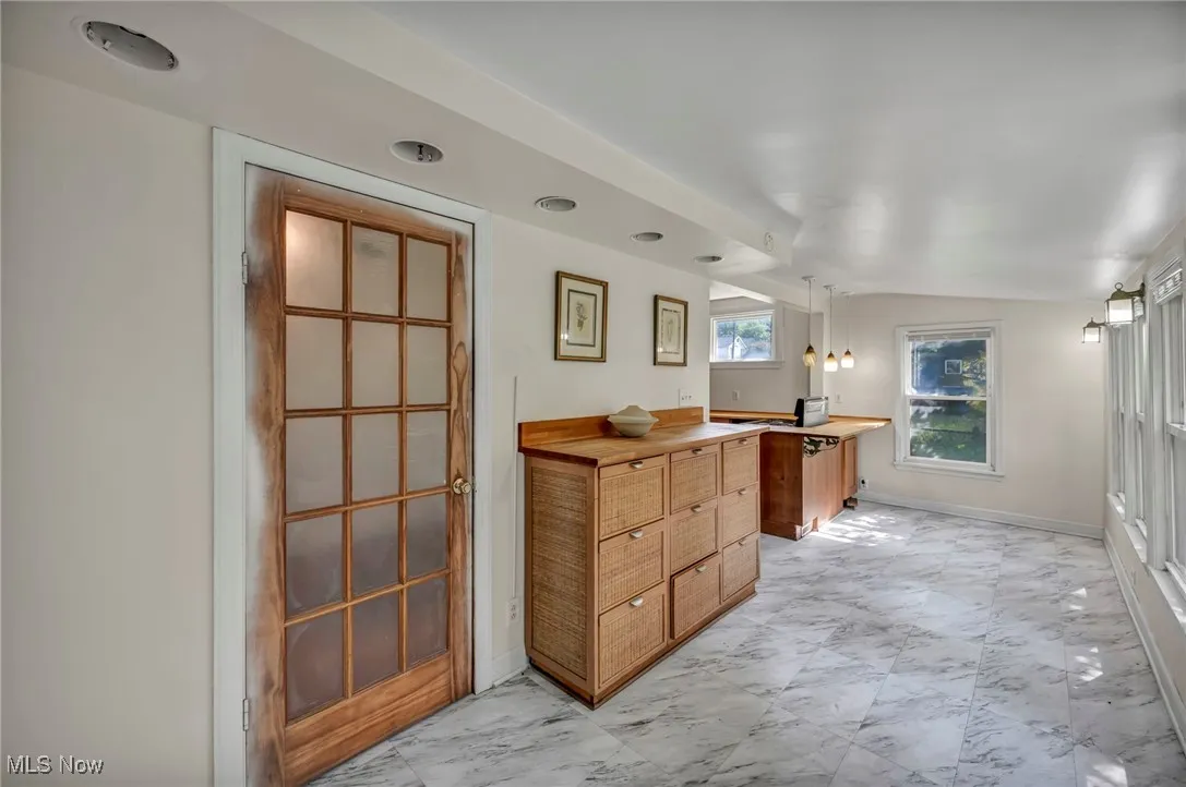 Full bath with vanity, marble look tile flooring, and vaulted ceiling