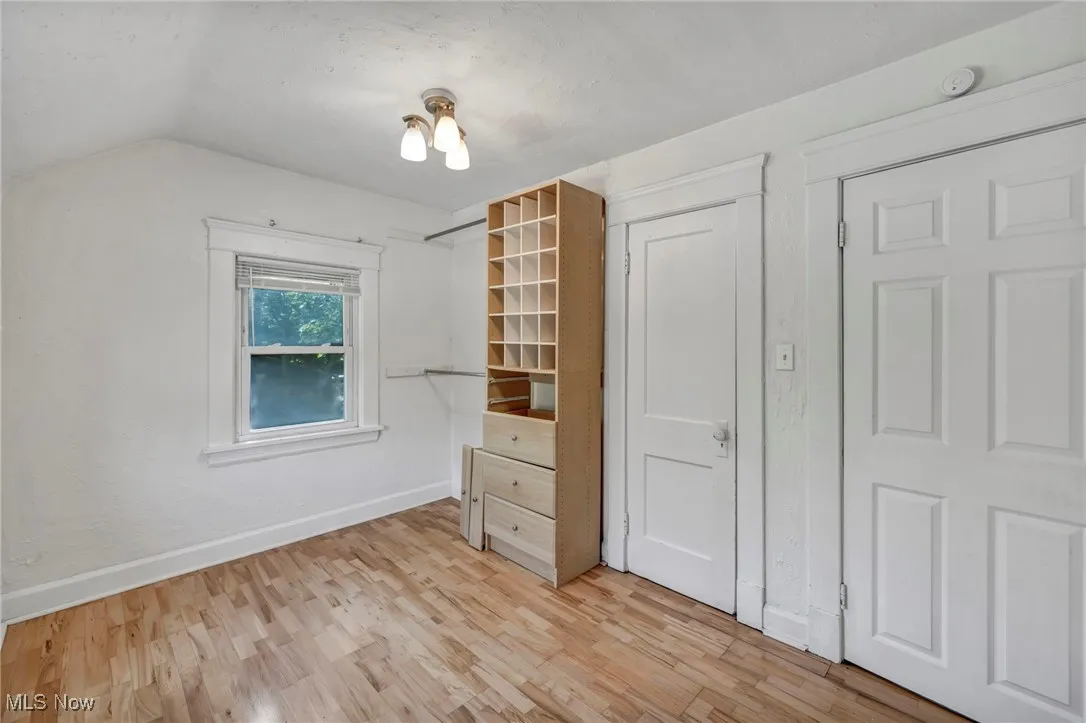 Unfurnished bedroom featuring light wood-type flooring and lofted ceiling