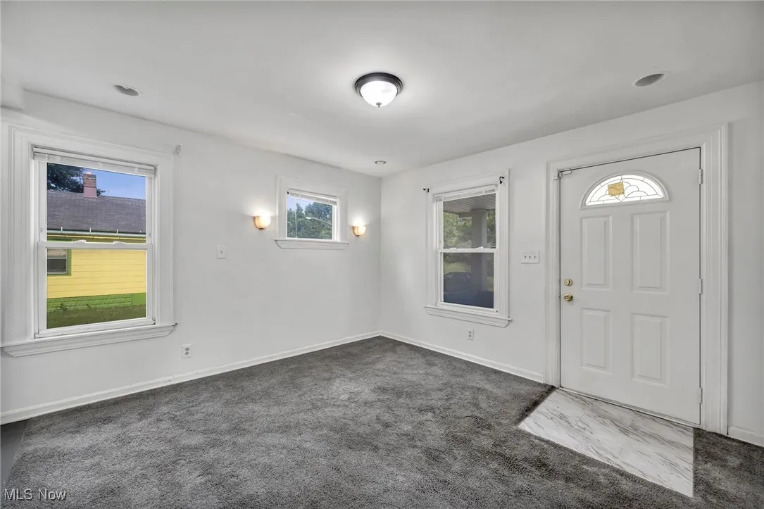 Foyer with dark carpet and baseboards