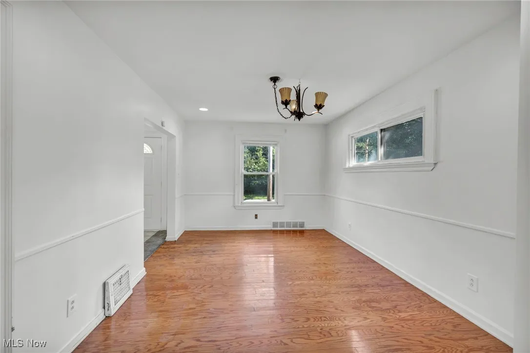 Empty room with wood finished floors, a chandelier, and recessed lighting