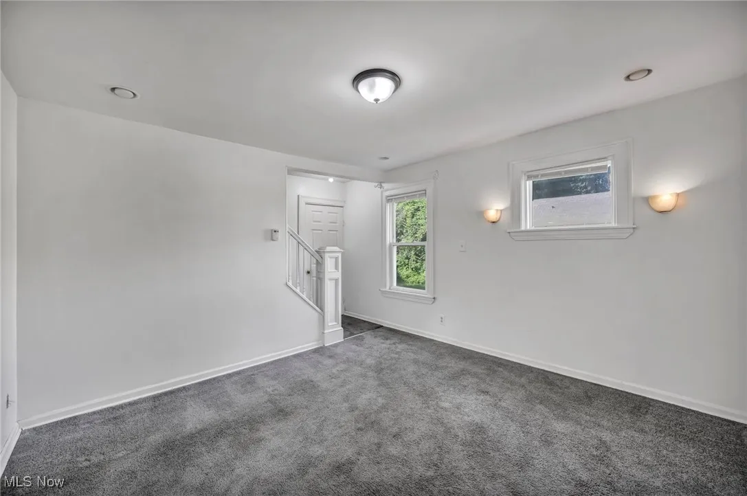 Spare room with dark colored carpet, stairs, and recessed lighting