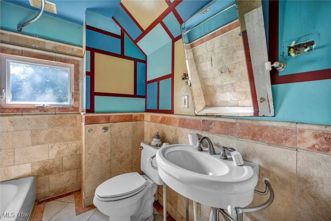 Bathroom featuring a tub to relax in, tile walls, tile patterned flooring, lofted ceiling, and a shower
