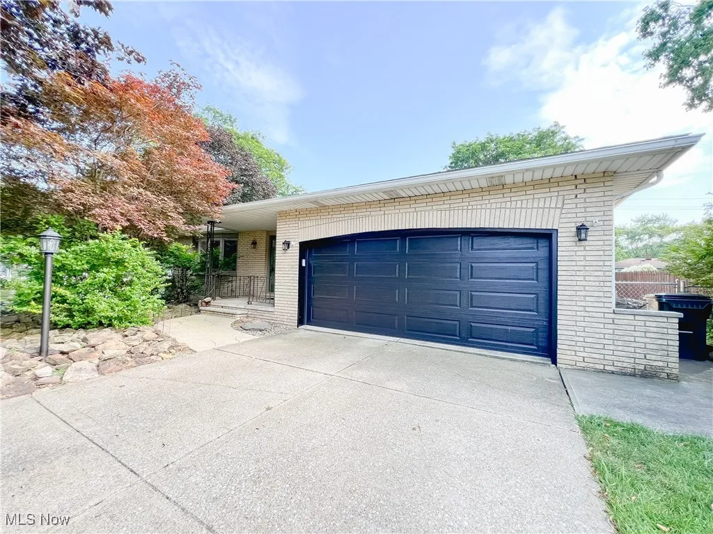 View of front of home with brick siding, driveway, and a garage