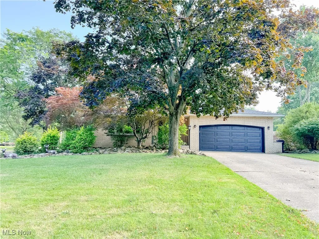 View of front of property featuring brick siding, a front yard, and concrete driveway